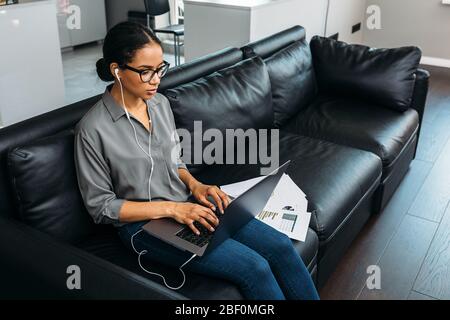 Junge Frau, die zu Hause mit Laptop und Dokumenten arbeitet. Geschäftsfrau, die von zu Hause aus arbeitet. Stockfoto