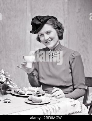 1930ER JAHRE MODISCHE BRÜNETTE FRAU MIT GLAS MILCH IM RESTAURANT SITZEN ESSEN SALAT ABENDESSEN ROLLE LÄCHELND BLICK AUF DIE KAMERA - F4517 HAR001 HARS FRAUEN GESUNDHEIT SCHMUCK MILCHPRODUKTE SITZEND KOPIE RAUM HALBE LÄNGE DAMEN PERSONEN TISCHDECKE VERTRAUEN B & W AUGENKONTAKT WEITWINKEL GLÜCK GETRÄNKE STILE FLÜSSIGKEIT ERNÄHRUNG LÄCHELN VERBRAUCHEN FLÜSSIGKEITSZUFUHR FRÖHLICH NAHRUNG STILVOLLE HOHE KRAGEN MODE PROTEIN ERFRISCHENDE JUNGE ERWACHSENE FRAU GETRÄNKE SCHWARZ UND WEISS KAUKASISCHEN ETHNIZITÄT HAR001 ALTMODISCH Stockfoto