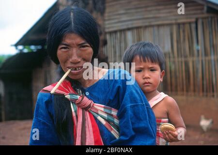 Die Frau des Lahu-Bergstammes in einem Dorf in Nordthailand trägt ihr Kind auf dem Rücken in einer bunten, gemusterten Schlinge. Stockfoto