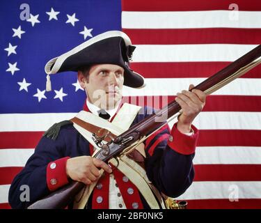 1970S MANN ALS KOLONIALEN KONTINENTALEN SOLDATEN GEKLEIDET RE-ENACTOR DES AMERIKANISCHEN REVOLUTIONÄREN KRIEGES KOLONIALFAHNE IM HINTERGRUND - KC6801 HAR001 HARS FREEDOM WARS TRICORN CONTINENTAL 1776 STEINSCHLOSS POLITIK UNIFORMEN KRIEG DER UNABHÄNGIGKEIT KONZEPTIONELLE RE-ENACTOR MUSKET STARS AND STRIPES REVOLTE AMERIKANISCHEN REVOLUTIONÄREN KRIEG 1770S KOLONIEN FEUERWAFFEN FEUERWAFFEN MITTE ERWACHSENE ROT WEISS UND BLAU KAUKASISCHE ETHNIZITÄT HAR001 ALTMODISCH Stockfoto