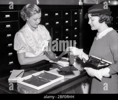 1930ER JAHRE VERKÄUFER HELFEN SHOPPER MIT EINER AUSWAHL VON STRUMPFWAREN SEIDENSTRÜMPFE - S5998 HAR001 HARS HALBE LÄNGE DAMEN PERSONEN FÜRSORGLICH VERTRAUEN B & W SHOPPER SHOPPER FÄHIGKEITEN BERUF FÄHIGKEITEN HIGH ANGLE KUNDENSERVICE BERUFE VERBINDUNG STRUMPFWAREN NYLONS AUSWAHL STILVOLLE ZUSAMMENARBEIT MITTE ERWACHSENE MITTE ERWACHSENE FRAU VERKÄUFER PROBEN JUNGE ERWACHSENE FRAU SCHWARZ UND WEISS KAUKASISCHE ETHNIZITÄT HAR001 ALTMODISCH SCHIERE Stockfoto