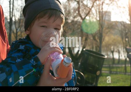 Ein kleiner Junge, der an Krankheit leidet Asthma bronchiale bekommen Behandlung mit Aerosol-Inhalator. Vermeidung von Komplikationen Stockfoto