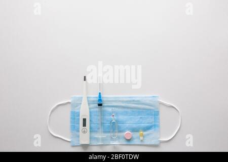 Medizinische Maske auf blauem, blauem Hintergrund.Gesichtsmaske. Maske für Krankheiten. Thermometer und Medikation. Einweg-Gesichtsbild. Medizinischer Atemverband Gesicht. Konzept der Quarantäne von Coronavirus. Stockfoto