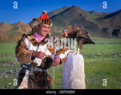 Mongolischer Adlerjäger, Kasachisch mit ausgebildetem Adler vor Bergen, Bajan-Oelgii Provinz, Mongolei Stockfoto