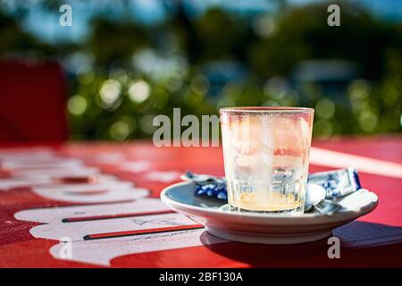Ein leeres Glas nach einem 'Bombon' (typisches Kaffeegetränk in der Region) auf einem roten Tisch auf der Terrasse. Stockfoto