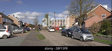 Wohnstraße Szene Straße Parkplatz in Straße & Häuser mit Autos auf original Rasen vor Garten jetzt gepflastert Platz für Fahrzeuge Essex England UK Stockfoto