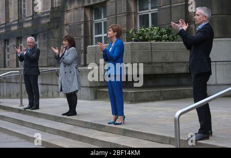 (Von links nach rechts) Malcolm Wright Generaldirektor NHS Schottland, Gesundheitsministerin Jeane Freeman, erster Minister Nicola Sturgeon und Dr. Gregor Smith Schottlands interimistischer Chefarzt applaudieren vor dem St. Andrew's House, dem Hauptquartier der schottischen Regierung in Edinburgh, Die lokalen Helden während der landesweiten Initiative „Clap for Carers“ am Donnerstag zu würdigen und zu unterstützen, die NHS-Arbeiter und Pförter gegen die Coronavirus-Pandemie anerkennt und bekämpft. Stockfoto