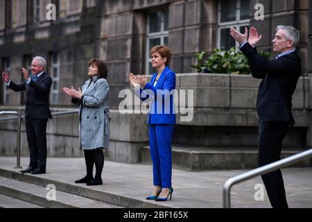 (Von links nach rechts) Malcolm Wright Generaldirektor NHS Schottland, Gesundheitsministerin Jeane Freeman, erster Minister Nicola Sturgeon und Dr. Gregor Smith Schottlands interimistischer Chefarzt applaudieren vor dem St. Andrew's House, dem Hauptquartier der schottischen Regierung in Edinburgh, Die lokalen Helden während der landesweiten Initiative „Clap for Carers“ am Donnerstag zu würdigen und zu unterstützen, die NHS-Arbeiter und Pförter gegen die Coronavirus-Pandemie anerkennt und bekämpft. Stockfoto