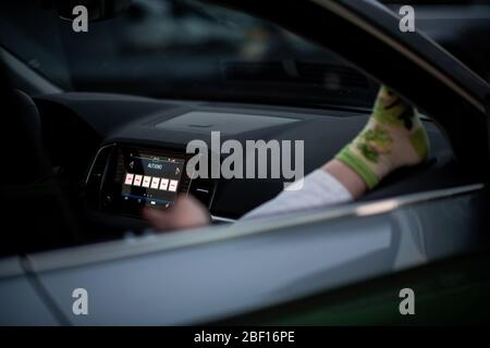 Oberhausen, Deutschland. April 2020. Ein Zuschauer hört sich das Programm 'Suddly Serious' an. Das Theater an der Niehburg in Oberhausen bietet ein Drive-in-Theater. Künstler treten auf einer Bühne auf einem Parkplatz vor den Zuschauern in Autos auf. Quelle: Fabian Strauch/dpa/Alamy Live News Stockfoto