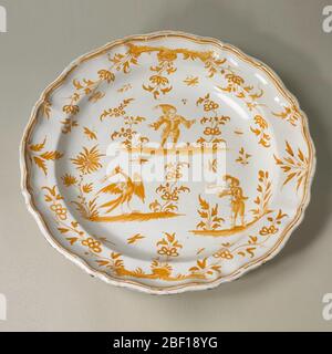 Ladegerät. Kreisförmige Form mit geformtem Rand. Monochrome ockerfarbene Dekoration zeigt Callot-Stil Figuren auf versetzten Terrassen und allover verstreut Blumen. Stockfoto