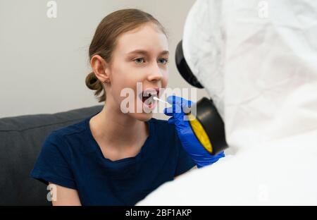 Männlicher Arzt in Schutzanzug und Maske, die Abstrichprobe vom Kind nimmt. Coronavirus-Test. Stockfoto