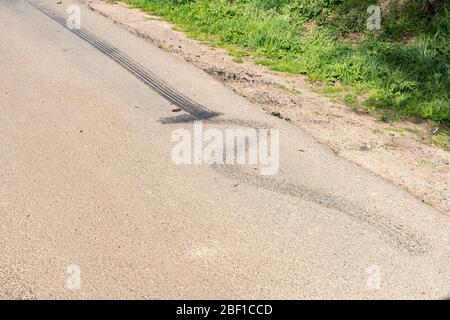 Schwarze Gummireifen-Skid-Markierungen auf einer Landstraße Stockfoto