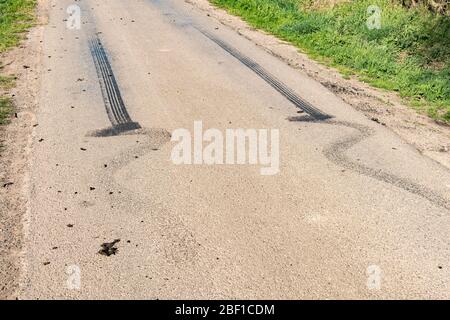 Schwarze Gummireifen-Skid-Markierungen auf einer Landstraße Stockfoto