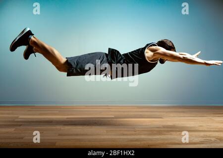 Ein Mann macht funktionelle Übungen in der Turnhalle auf grauem Hintergrund. Fitness-Konzept, Sport Körper, Körper positiv, Copy Space Stockfoto