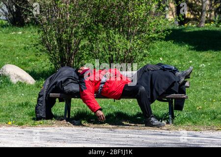 Ein Obdachloser mit roter Jacke schläft auf einer Bank im öffentlichen Park in Sofia, Bulgarien, Osteuropa, Balkan, EU Stockfoto