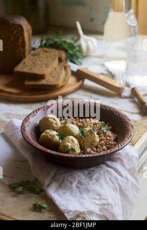 Fleischbällchen in saurer Sahne-Sauce, serviert mit Buchweizenbrei, Brot und Knoblauch. Rustikaler Stil. Stockfoto