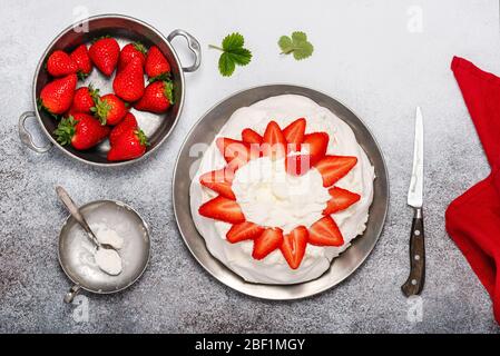 Hinzufügen von Erdbeeren zu Schlagsahne auf Baiser. Schritt für Schritt Rezept von Pavlova Kuchen mit Erdbeeren. Draufsicht. Kopierbereich. Stockfoto
