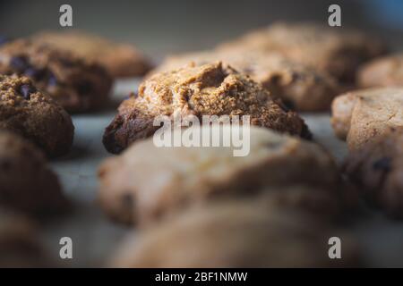 Hausgemachte Schokoladenkekse in einer Reihe auf einem Holzbrett Stockfoto