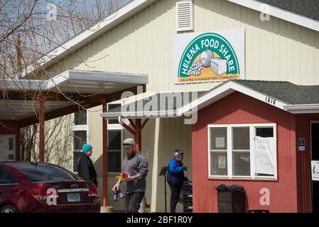 Helena, Montana - 16. April 2020: Mann mit Getränken, der während der Coronavirus Covid-19-Shutdown-Pandemie aus Helena Food Share ausläuft. Lebensmittel und Mahlzeiten. Stockfoto