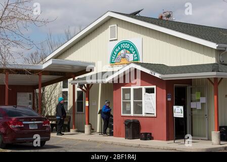 Helena, Montana - 16. April 2020: Zwei kaukasische Frauen mit Masken warten in Helena Food Share auf Lebensmittel, die während des Coronavirus benötigt werden. Stockfoto