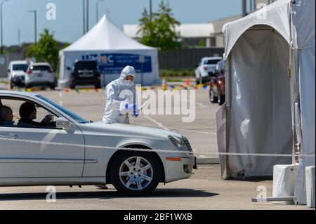 Sugar Land, Texas - 16. April 2020: In voller Schutzkleidung gekleidet sammelt ein Gesundheitsarbeiter Informationen von älteren Paaren, die in ihrem sitzen Stockfoto