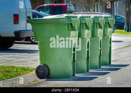 Horizontale Aufnahme von vier Müllcontainern in Wohnhäusern, die auf der Straße aufgestellt sind, um sie abholen zu können. Stockfoto