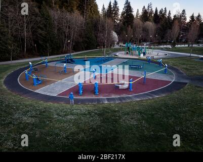 Ein einstehendes Kind, das nicht identifizierbar ist und neben einem Spielplatz steht, der aufgrund der Covid-Pandemie 19 mit Klebeband verschlossen wurde Stockfoto