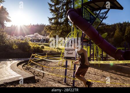 NORTH VANCOUVER, BC, KANADA - APR 11, 2020: Kinder spielen vor einem geschlossenen Spielplatz in einem öffentlichen Park in North Vancouver mit Klebeband zu Stockfoto