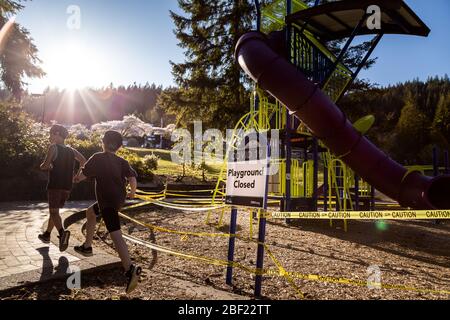 NORTH VANCOUVER, BC, KANADA - APR 11, 2020: Kinder spielen vor einem geschlossenen Spielplatz in einem öffentlichen Park in North Vancouver mit Klebeband zu Stockfoto