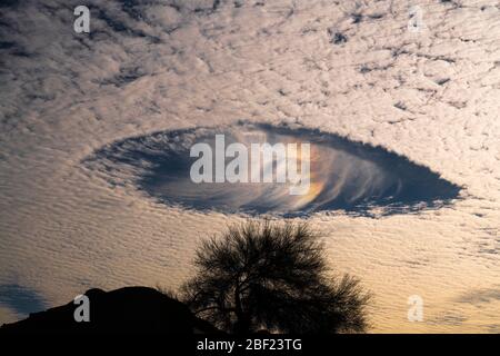 Fallsträhne Löcher mit Regenbogen in Altokumuluswolken, die wie Raumschiffe am Morgenhimmel aussehen Stockfoto