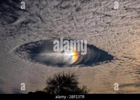 Fallsträhne Löcher mit Regenbogen in Altokumuluswolken, die wie Raumschiffe am Morgenhimmel aussehen Stockfoto