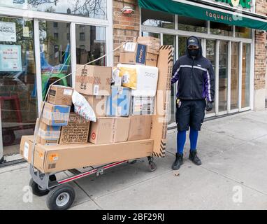 New York, NY - 16. April 2020: FedEx-Arbeiter Kelvin Nunez als wichtiger Arbeiter sah Pakete liefern inmitten der COVID-19-Pandemie in Inwood Nachbarschaft von Manhattan Stockfoto