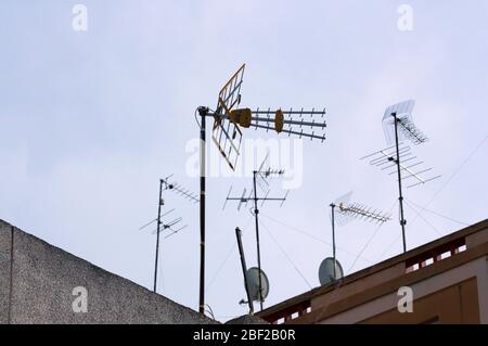 Einige Antennen des digitalen terrestrischen Fernsehens (DTT) zusammen mit älteren und einigen Satellitenschüsseln, auf den Dächern von Gebäuden mit Platz für Texte in Stockfoto