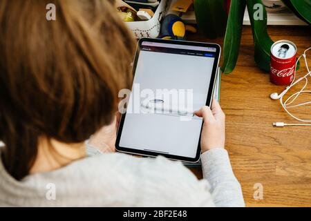 Paris, Frankreich - Apr 16, 2020: Frau sucht Inspektion neue Kamera auf Apple Computers Internet-Website auf iPad Pro Tablet in Raum-Umgebung präsentiert neue iPhone SE Stockfoto