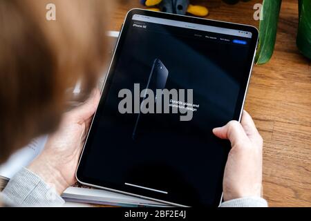Paris, Frankreich - Apr 16, 2020: Langlebiges Glas- und Aluminiumdesign - Frau auf der Apple Computers Internet-Website auf dem iPad Pro Tablet in Raumumgebung präsentiert neues iPhone SE Stockfoto