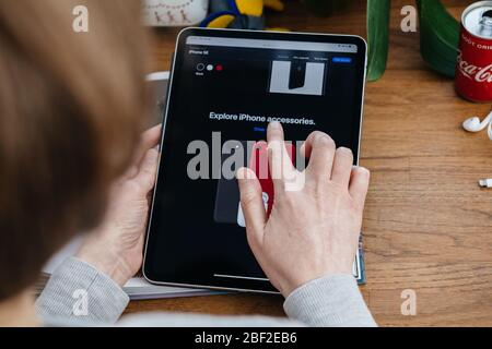 Paris, Frankreich - Apr 16, 2020: Entdecken Sie neue Accessoires - Frau auf der Apple Computer Internet-Website auf iPad Pro Tablet in Raum-Umgebung präsentiert neue iPhone SE Stockfoto