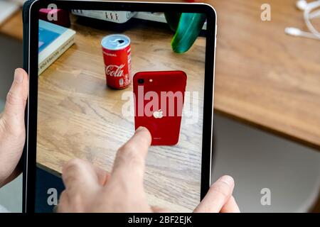 Paris, Frankreich - Apr 16, 2020: Paar vergleichen auf Apple Computers Internet-Website auf iPad Pro Tablet in Raum-Umgebung präsentiert neue iPhone SE mit AR Vergleich mit Coke Can Stockfoto