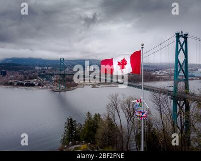 Slow Motion kanadische Flagge winkt am Prospect Point im Stanley Park mit der Lions Gate Bridge im Hintergrund in Vancouver, BC. 4K 24 BILDER/S Stockfoto