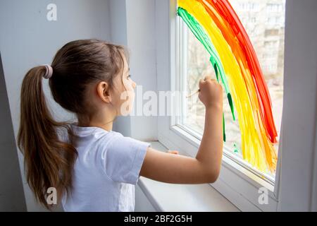 Jagt den Regenbogen-Fashmob. Das Kind zeichnet einen Regenbogen auf das Fenster und hofft, dass alles gut wird. Regenbogen am Fenster. Quarantäne während eines Stockfoto