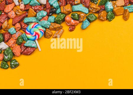 Lollipop und Bonbons auf gelbem Hintergrund. Süßigkeiten in Form von farbigen Steinen. Bunte Süßigkeiten. Kopierraum Stockfoto
