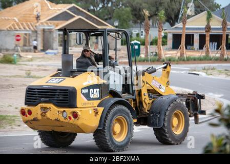 Traktor-Fahrer bewegen Ausrüstung, wo für neue Baumaßnahmen in Zentral-Florida während Coronavirus Aufenthalt zu Hause bestellen benötigt Stockfoto