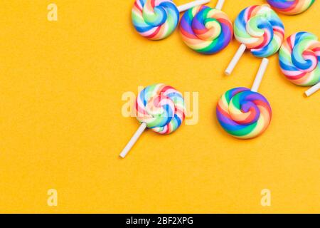 Lollipops schließen sich an. Bunte Süßigkeiten auf gelbem Hintergrund. Festliche Dekoration. Kopierraum Stockfoto