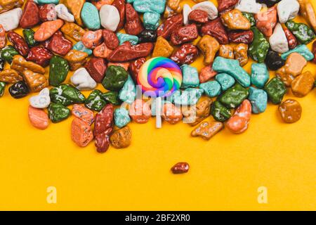 Lollipop und Bonbons auf gelbem Hintergrund. Süßigkeiten in Form von farbigen Steinen. Bunte Süßigkeiten. Kopierraum Stockfoto
