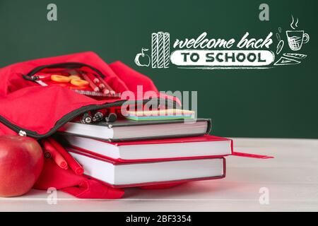 Rucksack auf dem Tisch in der Nähe Tafel mit Text WILLKOMMEN ZURÜCK IN DER SCHULE Stockfoto