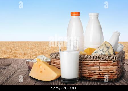 Verschiedene Milchprodukte auf Holztisch im Weizenfeld Stockfoto