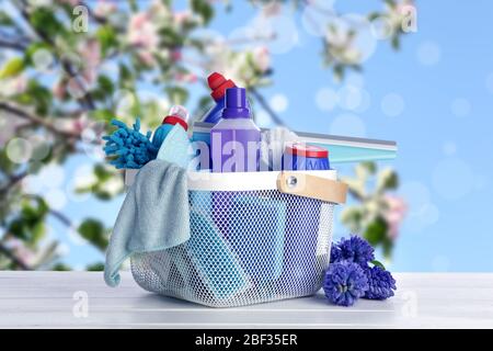 Set von Reinigungsmitteln und Frühlingsblumen auf Holztisch im Freien Stockfoto