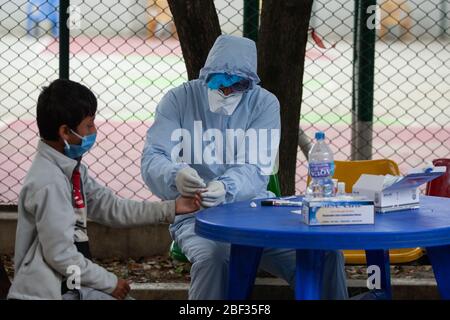 Kathmandu, Nepal. April 2020. Ein in einem Schutzanzug gekleideter Gesundheitsarbeiter nimmt Blutproben von einem Jungen, der vor kurzem eine Reisegeschichte außerhalb des Landes im provisorischen Schnelltestzentrum für Coronavirus (COVID-19) hat. Nepal hat in den letzten 48 Stunden keine neuen Fälle von Coronavirus gemeldet. (Foto von Prabin Ranabhat/Pacific Press) Quelle: Pacific Press Agency/Alamy Live News Stockfoto