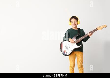 Kleiner Junge, der Gitarre auf leichtem Hintergrund spielt Stockfoto