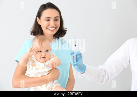 Kinderarzt geimpft kleines Baby auf hellem Hintergrund Stockfoto