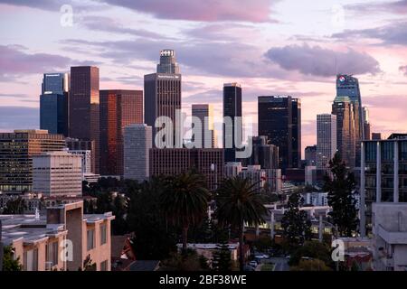Skyline von Los Angeles bei Sonnenuntergang mit bunten rosa und goldenen Wolken am Himmel, wie aus Angelino Heights Nachbarschaft betrachtet Stockfoto